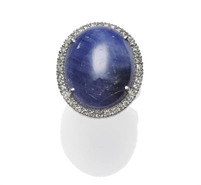 Lot 373 - An 18 Carat White Gold Sapphire and Diamond Cluster Ring, the large cabochon sapphire within a...