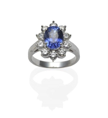 Lot 374 - A Sapphire and Diamond Cluster Ring, the oval mixed cut sapphire within a border of ten round...