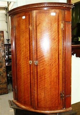 Lot 505 - A Georgian oak and mahogany cross banded bow front corner cabinet