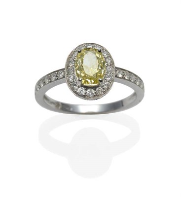 Lot 382 - A Yellow and White Diamond Cluster Ring, the oval cut yellow diamond within a border of white...