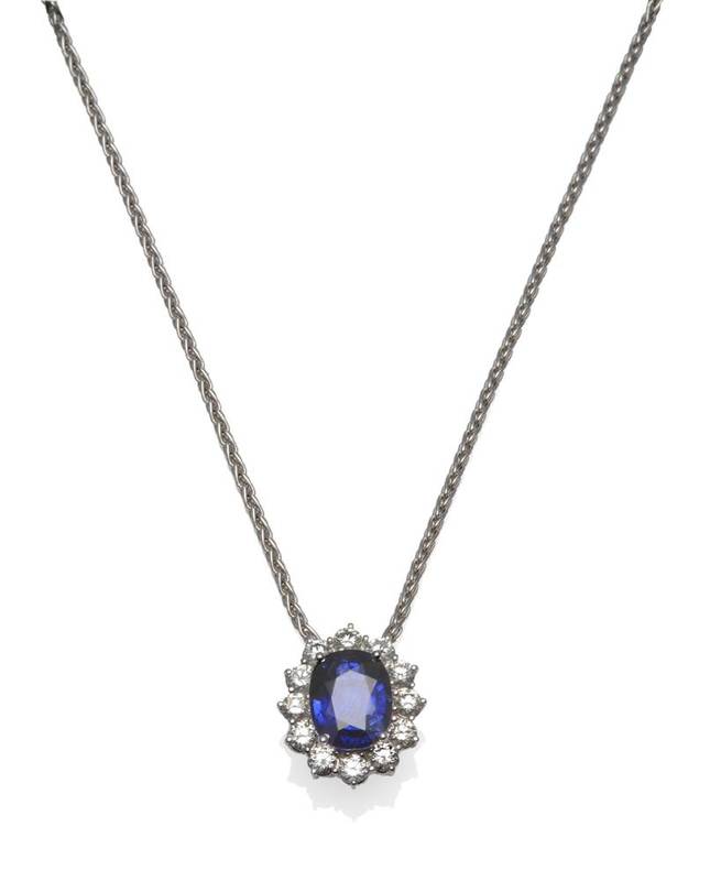 Lot 392 - A Sapphire and Diamond Cluster Pendant, the oval mixed cut sapphire within a border of round...