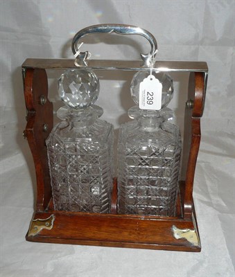 Lot 239 - An oak tantalus with plated mounts and two cut glass decanters with stoppers and a key