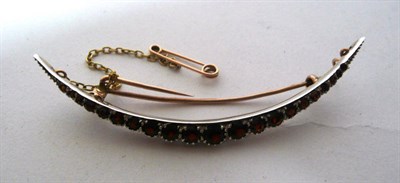 Lot 400A - A garnet crescent brooch, round brilliant stones graduate along the length, in white claw settings