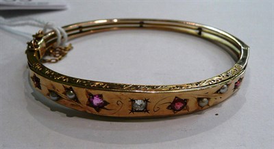 Lot 55 - A bangle set with an old cut diamond, garnets and seed pearls