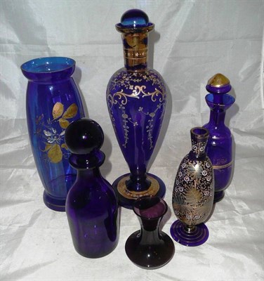 Lot 303 - A blue glass decanter and stopper, four blue glass vases and an amethyst vase