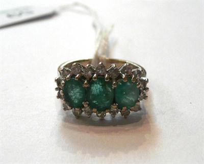 Lot 59 - An 18 Carat White Gold Emerald and Diamond Triple Cluster Ring, the oval cut emeralds within a...