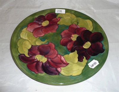 Lot 236 - A Walter Moorcroft 'Clematis' charger, on a green ground, impressed factory marks, painted blue...