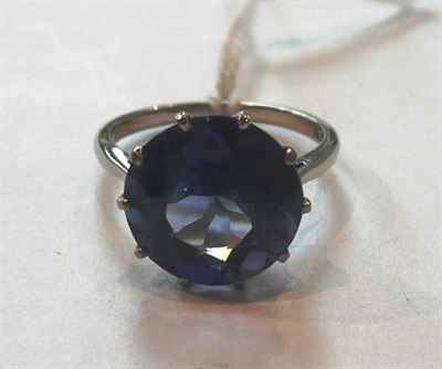 Lot 307 - A Synthetic Sapphire Solitaire Ring, the round brilliant cut sapphire in a white claw setting...