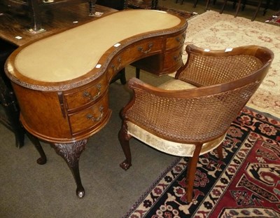 Lot 555 - A walnut kidney-shaped desk and a double caned begere armchair