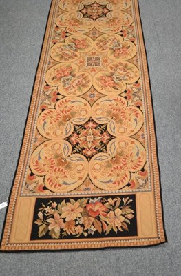 Lot 487 - A European design needlepoint runner, China, the beige field of floral design enclosed by...