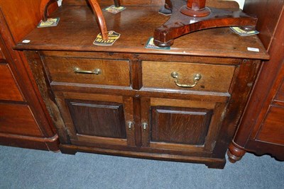 Lot 597 - A small oak side cupboard with two drawers and two panel doors