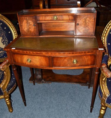 Lot 610 - A mahogany bow fronted writing desk with green leather top and gallery