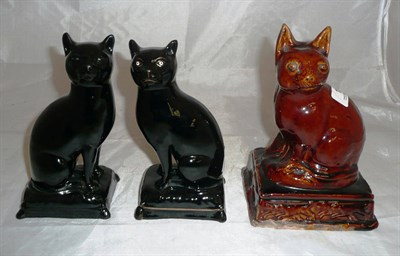 Lot 13 - Two late Victorian black glazed seated cat figures and a brown glazed example (3)