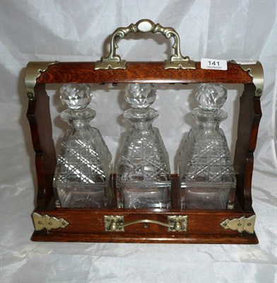 Lot 141 - An oak cased tantalus (one decanter cracked)