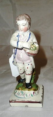 Lot 235 - A late 18th century pearlware figure of a boy holding a basket