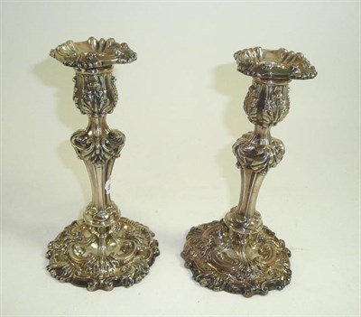 Lot 243 - A pair of Georgian silver candlestick with repousse decoration, each with an armorial