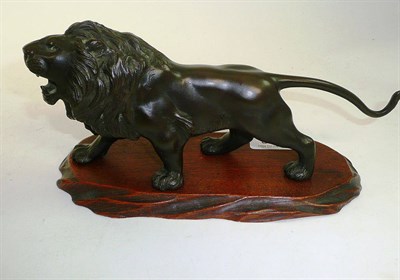 Lot 351 - A Japanese bronze lion, signed, on an oval wooden base