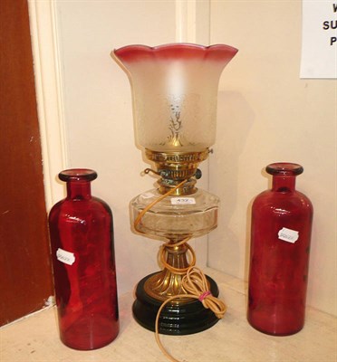 Lot 432 - A pair of cranberry bottles and an oil lamp fitted for electricity