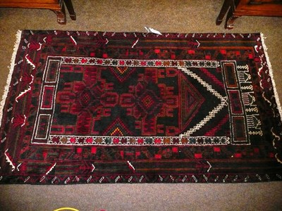 Lot 575 - A red ground rug with a blue geometric design