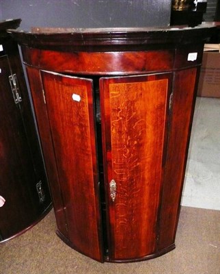 Lot 630 - A George III oak and mahogany crossbanded bowfront hanging corner cupboard