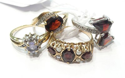 Lot 111 - Three garnet set rings and a tanzanite and diamond cluster ring