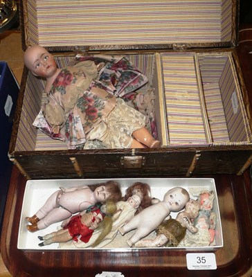 Lot 35 - Seven small bisque dolls and a doll's portmanteau