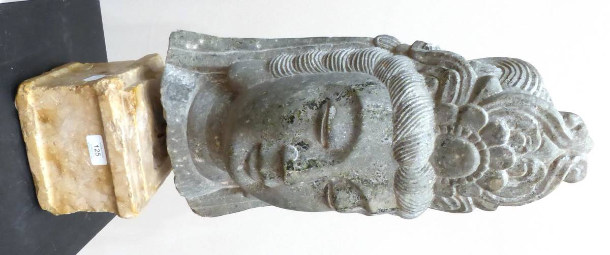 Lot 125 - A Stone Head of Guanyin, in Archaic style, mounted on a stone base, 66cm high