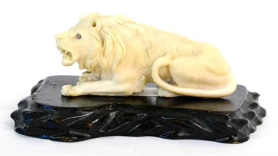 Lot 138 - A Japanese Carved Ivory Figure of a Seated Lion, late 19th century, the beast naturalistically...