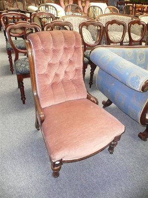 Lot 511 - A Victorian walnut framed roll back armchair upholstered in pink velour