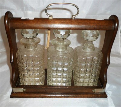 Lot 60 - An oak three bottle tantalus with plated mounts