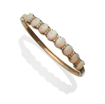 Lot 232 - A 14 Carat Gold Opal and Diamond Bangle, eight oval opals spaced by trios of round brilliant...