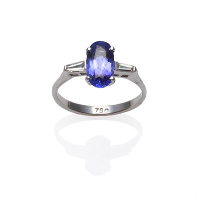 Lot 254 - A Tanzanite and Diamond Three Stone Ring, an oval cut tanzanite with a tapered baguette cut diamond