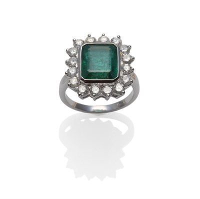Lot 259 - An Emerald and Diamond Cluster Ring, the emerald-cut emerald within a white rubbed over...
