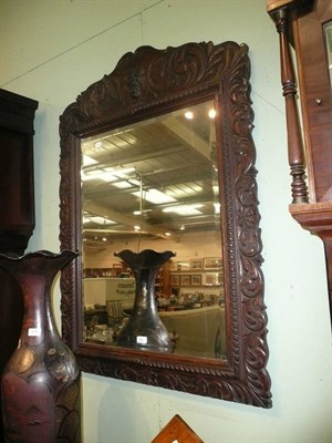 Lot 758 - A wall mirror in a foliate carved oak frame