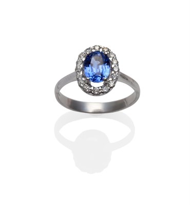 Lot 274 - An 18 Carat White Gold Sapphire and Diamond Cluster Ring, the oval mixed cut sapphire within a...