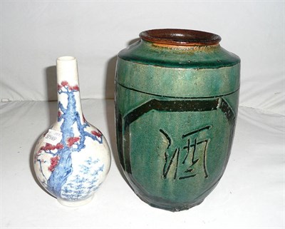 Lot 3 - A large  Ming dynasty Chinese stoneware green glazed wine jar (with jiu [wine] incised...