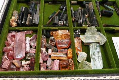 Lot 440 - A tray of rough gemstones including tourmaline crystals, a calcite rhomb, semi polished/faceted...