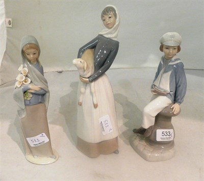 Lot 533 - Three Lladro figures modelled as boy holding a toy yacht, girl with lilies and a girl with a lamb