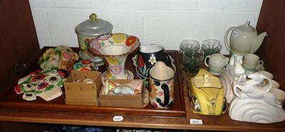 Lot 222 - Shelf including Susie Cooper coffee set, yellow racing car teapot, pair of bookends, wall...