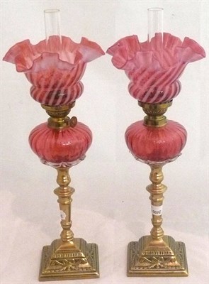 Lot 168 - A pair of Victorian brass oil lamps with cranberry fonts and cranberry and vaseline glass shades