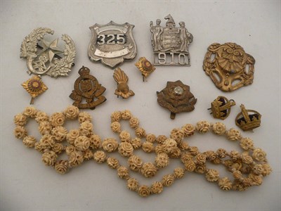 Lot 425 - An ivory necklace and a quantity of cap badges