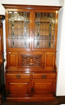 Lot 506 - An early 20th century oak carved and glazed bookcase, with dentil cornice above leaded glazed...