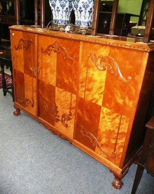 Lot 685 - An early 20th century bird's eye maple side cabinet with three drawers and claw and ball feet