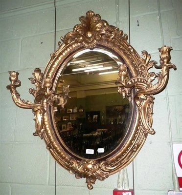 Lot 783 - A reproduction giltwood oval mirror with girandole