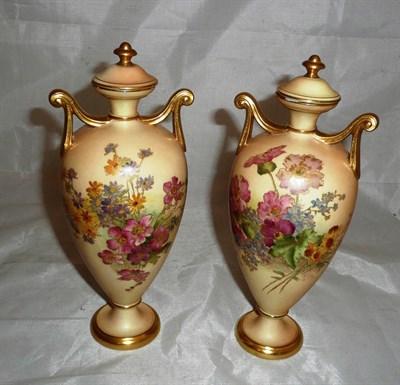 Lot 92 - A pair of Royal Worcester blush ivory twin handled vases and covers