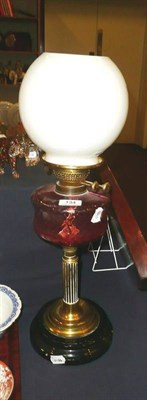 Lot 134 - A brass and cranberry glass oil lamp