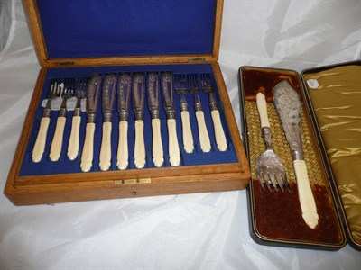 Lot 7 - A cased set of twelve fish knives and forks with carved ivory handles and the corresponding...