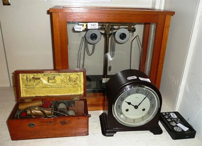 Lot 147 - Enfield mantel clock, balance scales, box of weights and a shock machine (3)