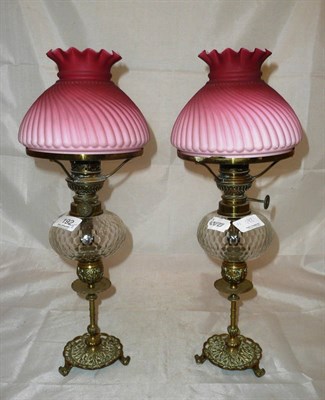 Lot 192 - A pair of Victorian brass oil lamps with clear glass reservoirs and pink opaque shades