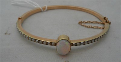 Lot 218 - A 15ct gold stiff hinged bangle set with an opal and seed pearls